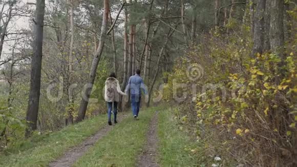 年轻的幸福夫妇走在美丽的秋天森林里4K视频的预览图