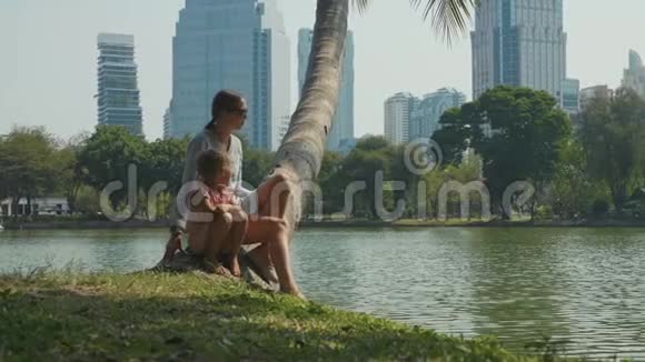 家庭在公园放松湖和摩天大楼背景视频的预览图