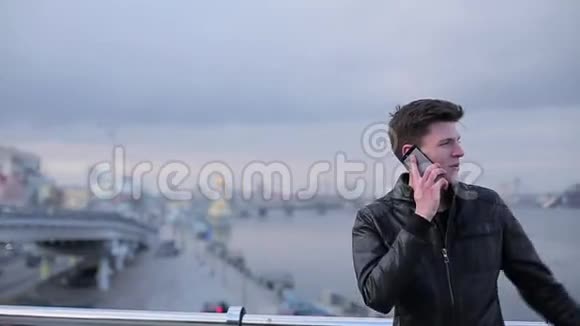 黑发男子在城市河畔打手机视频的预览图