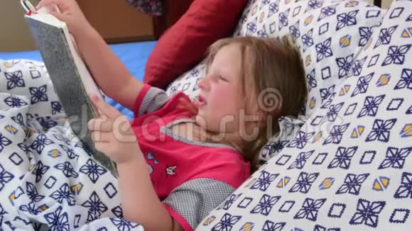 床上的小女孩女孩看着一本老父亲的日记小女孩看着床上的一本旧书家庭概念视频的预览图