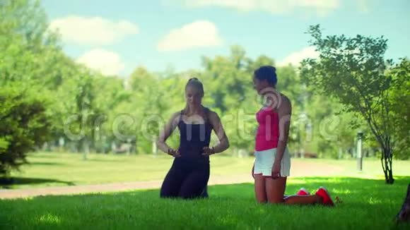 公园里跪在绿草上说话的女孩们视频的预览图