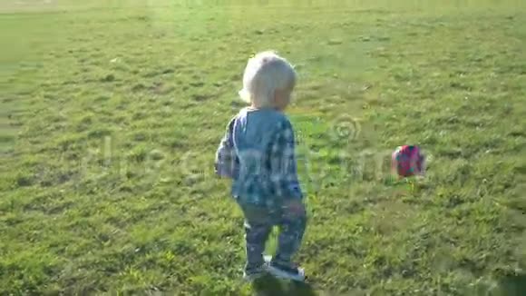 一个半岁的男孩高兴地在球场上追逐球视频的预览图