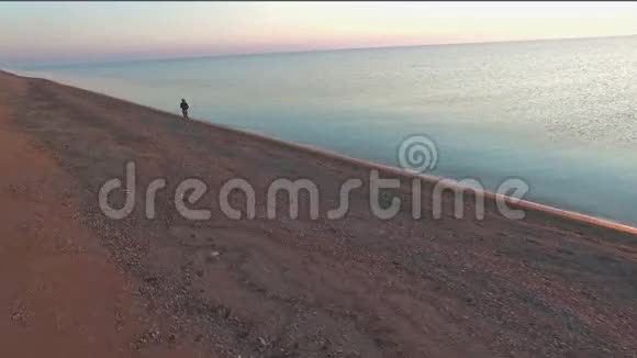 在金色的夕阳下女人和狗在海滩上自由奔跑健身女孩和她的宠物一起锻炼视频的预览图