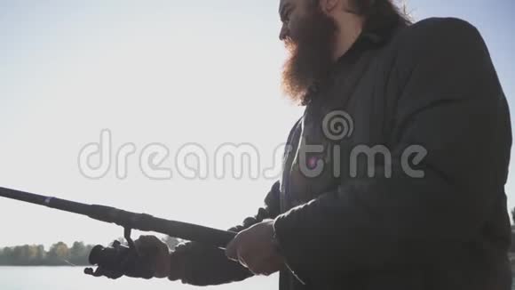 长胡子的人在河上钓鱼渔夫拿着鱼竿在河上河流捕鱼慢动作视频的预览图