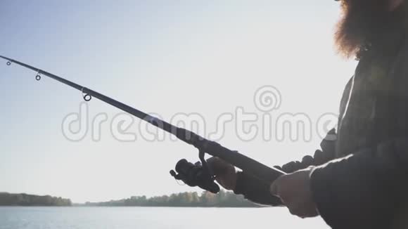大胡子渔夫拿着鱼竿在河上钓鱼河流捕鱼慢动作视频的预览图
