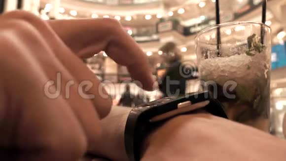 一个男人在咖啡馆用他的智能手表4K特写镜头视频的预览图