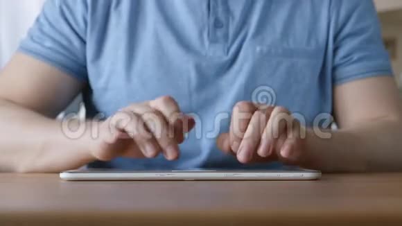年轻人在家里桌子上用平板电脑打字的手视频的预览图