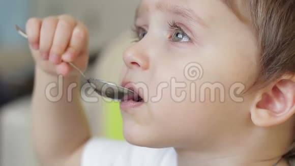 男孩用勺子吃食物孩子的脸是特写的视频的预览图