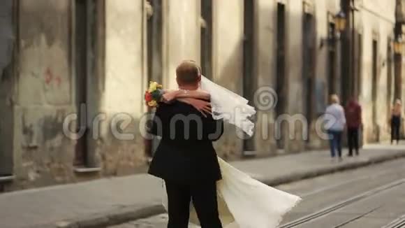 快乐的新郎拥抱在市中心亲吻新娘视频的预览图