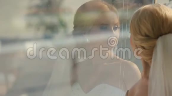 年轻漂亮的新娘透过窗户看着外面的新郎视频的预览图