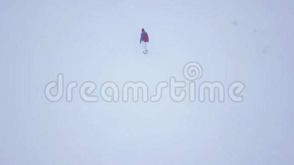 飞过一个孤独的旅游女孩她走在一座被雪覆盖的山顶上不舒服不友好视频的预览图