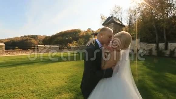 新婚快乐的新婚夫妇在中世纪城堡的院子里温柔地接吻视频的预览图