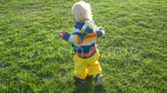 一个半岁的男孩高兴地在球场上追逐球视频的预览图
