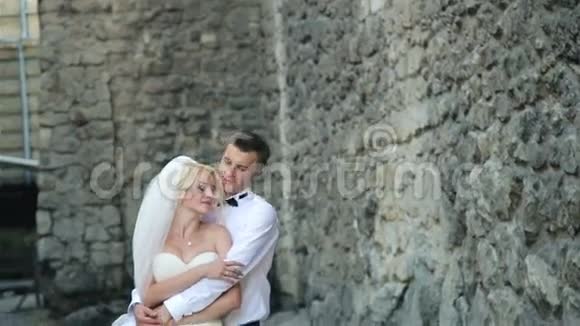 一对美丽的新婚夫妇在石墙前视频的预览图