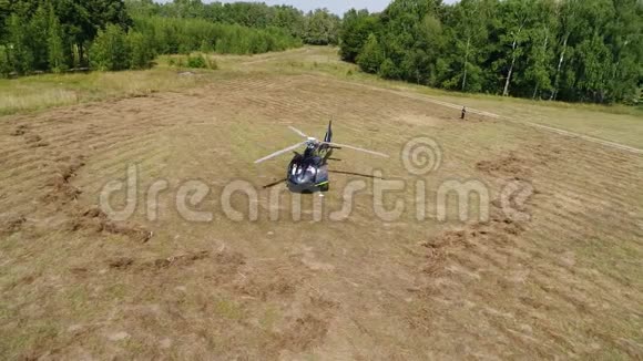 直升机在空中盘旋直升机降落在森林带附近的田野上直升机降落在黄草上视频的预览图