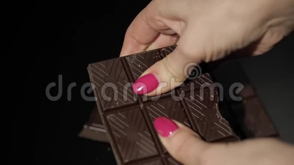 女人打破黑色巧克力棒特写镜头慢动作视频的预览图