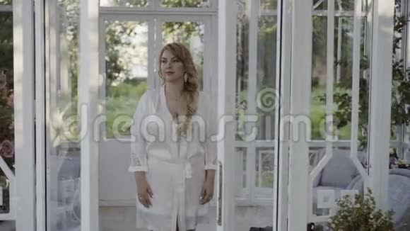 可爱的金发女郎穿着内衣敞开的玻璃门视频的预览图