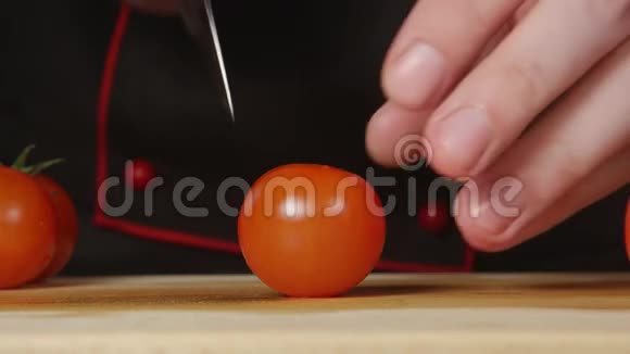 厨师在厨房的切割板上切一个樱桃番茄视频的预览图