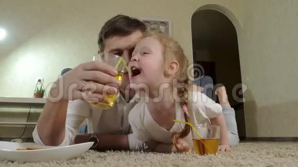 男人和女儿看电视坐在地上喝果汁视频的预览图