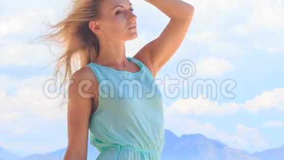 一个金发女孩的肖像她在风中披着头发披着云彩视频的预览图