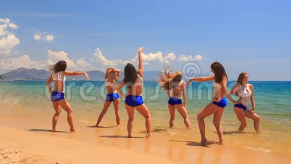 穿着白色蓝色衣服的啦啦队员在海滩上跳舞视频的预览图