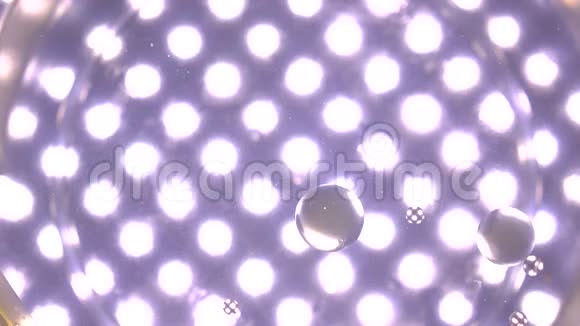 油滴在多个点灯紫色背景下落入水中科学实验概念4K视频视频的预览图