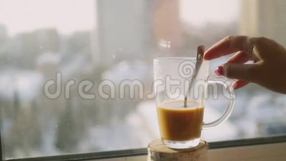 用勺子搅拌黑咖啡和牛奶在透明的杯子里搅拌背景是外面的城市景观视频的预览图