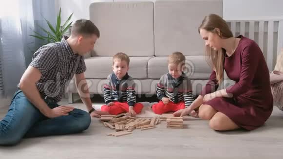 一家人的妈妈爸爸和两个双胞胎兄弟一起在地板上用木块做游戏视频的预览图
