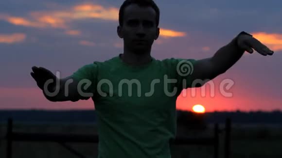 男人在跳舞在美丽的日落背景上挥动手臂红色的天空和人类的轮廓视频的预览图