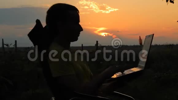 日落时分一个快乐的商人带着笔记本电脑在野外工作男人在椅子上荡秋千视频的预览图