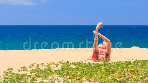 穿着红色衣服的金发女孩躺在沙滩上双手靠近绿色的爬行动物视频的预览图