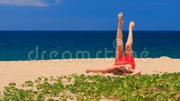 穿红衣服的金发女孩躺在沙滩上用腿剪羊毛视频的预览图