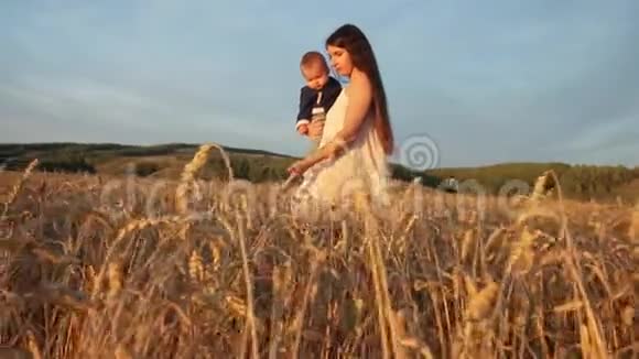 日落时分一位年轻的母亲和她的儿子在麦田里散步视频的预览图