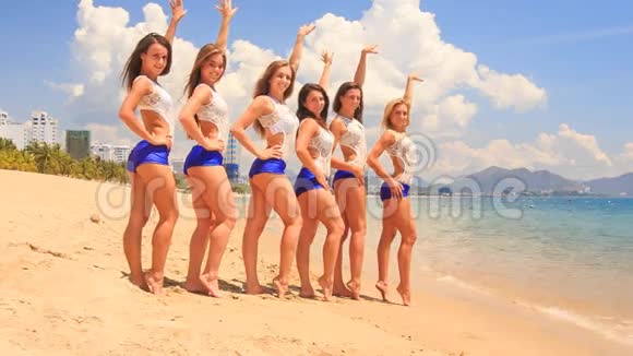 啦啦队员穿着白色蓝色的衣服站在队伍里在海滩上遇到水视频的预览图