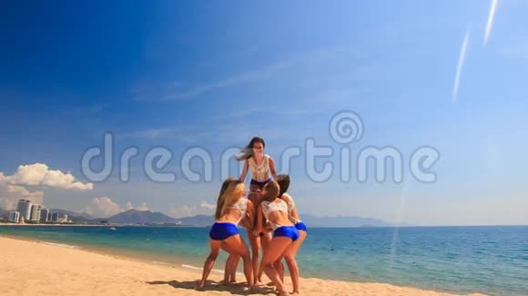 穿着白色蓝色服装的啦啦队员在沙滩上抛视频的预览图