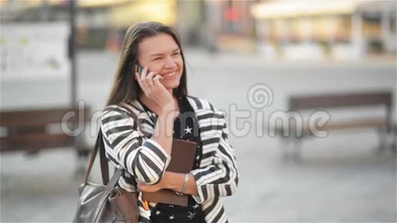 年轻快乐兴奋的笑女在手机上说话女孩在街上挥手城市的背景视频的预览图