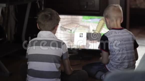 两个男孩坐在家里玩电脑游戏视频的预览图