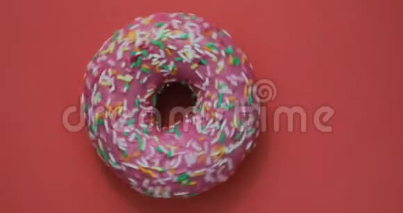 明亮而多彩的甜甜圈特写镜头旋转在红色背景上美味的甜甜甜面圈视频的预览图