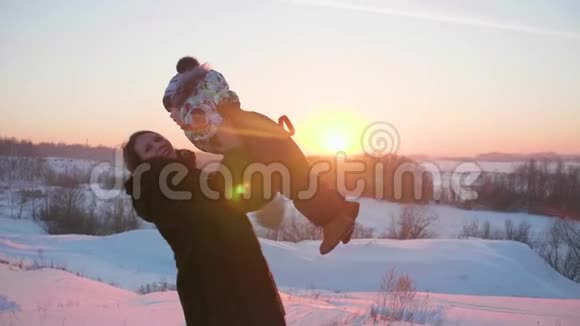 一个带着孩子在冬季公园玩耍的小女孩在新鲜空气中游走日落视频的预览图