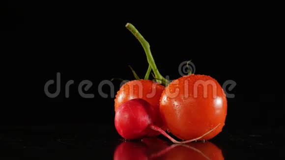 新鲜的西红柿和萝卜在黑色的背景上旋转滴着水滴视频的预览图