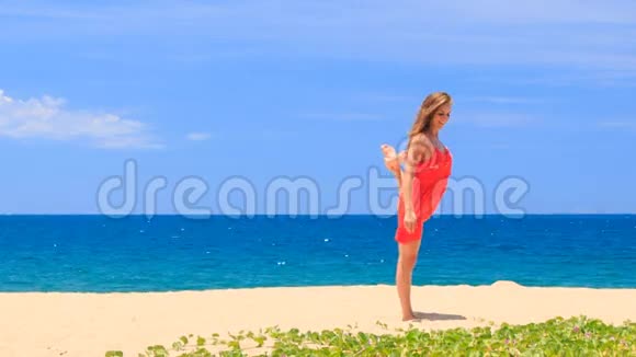 金发女孩红色显示位置双手腿秤在沙子上视频的预览图