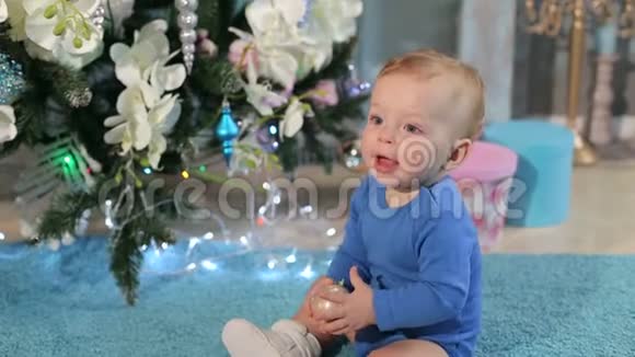 一个可爱的小男孩在一棵装饰好的圣诞树附近的肖像视频的预览图