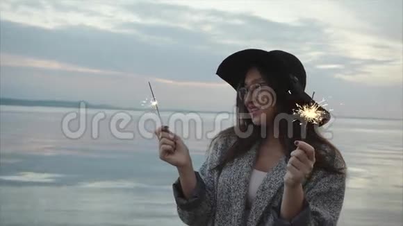 美丽幸福的女人在日落时在海上的海岸上欢腾视频的预览图