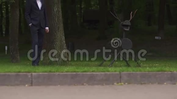 英俊自信的新郎正在绿林中等待新娘靠近创意木鹿的身影视频的预览图