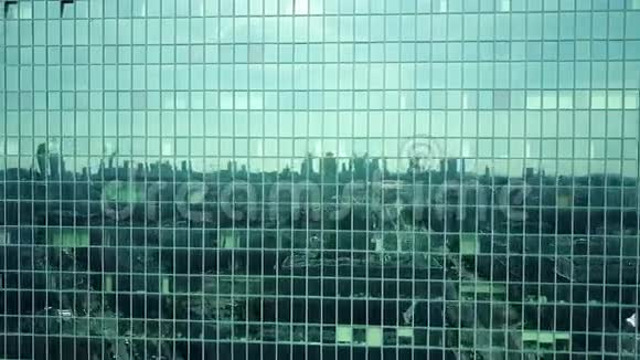 阳光明媚的一天现代办公楼窗户的空中拍摄反映了城市景观4K视频视频的预览图
