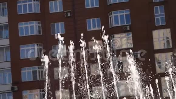 阳光明媚的一天城市建筑背景上的喷泉流慢动作视频的预览图