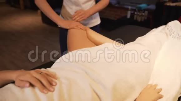 年轻女子在美容院做脚部按摩关门玛瑟揉捏一个年轻漂亮女孩的脚和腿视频的预览图