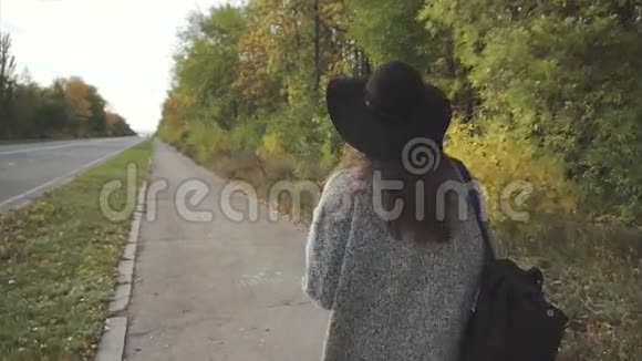 戴着黑帽子戴着眼镜走在秋街上的年轻美女视频的预览图