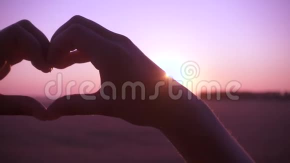 女孩的手在日出时做心的象征视频的预览图