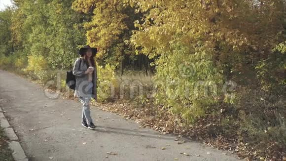 戴着黑帽子的年轻美女走在秋街上视频的预览图